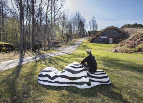 Taideteos luonnossa jonka päällä ihminen istuu